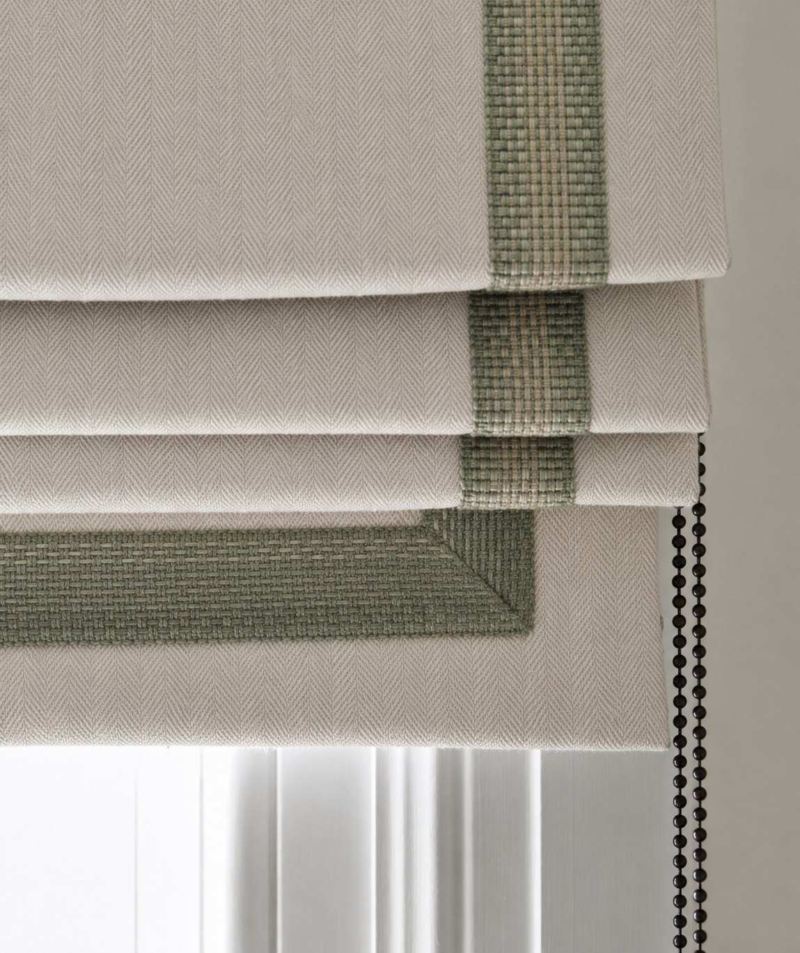 Detail of a woven Roman blind with a fitted braid trim